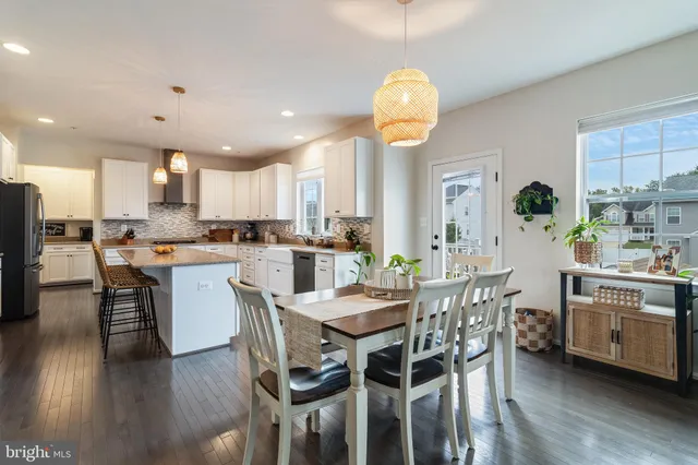 a kitchen with stainless steel appliances a dining table chairs and wooden floor