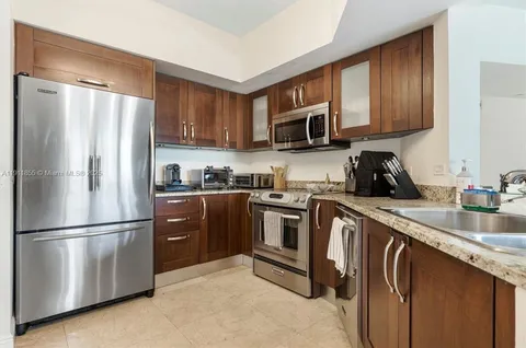 a kitchen with stainless steel appliances granite countertop a refrigerator a sink dishwasher a stove top oven a refrigerator with wooden cabinets