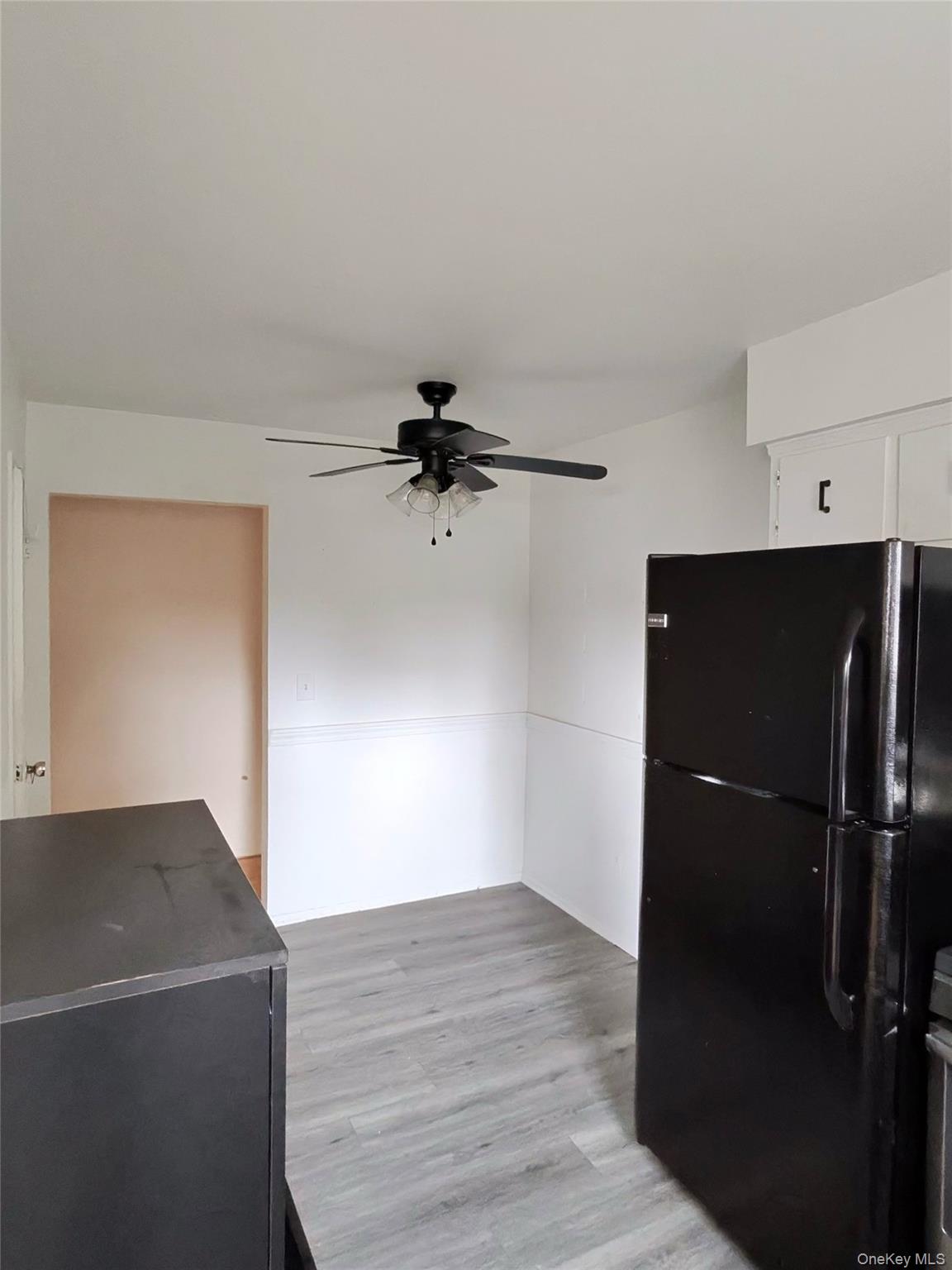 285 Sneden Place West, Unit 285 Spring Valley, NY 10977 - Photo 7 of 7 a view of a refrigerator in kitchen and an empty room with wooden floor