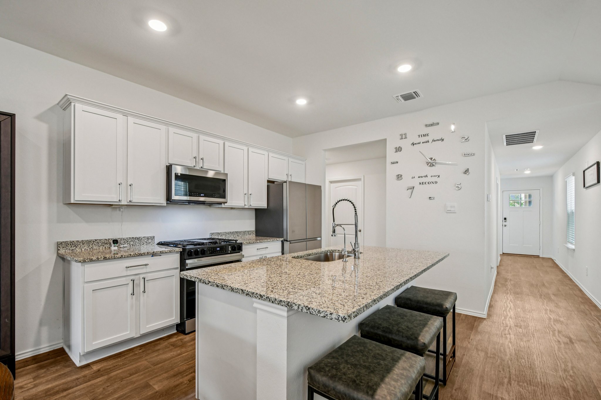 519 Sandringham Loop Kyle, TX 78640 - Photo 15 of 32 Kitchen with stainless steel appliances, white cabinets, dark wood-style floors, a breakfast bar area, and recessed lighting
