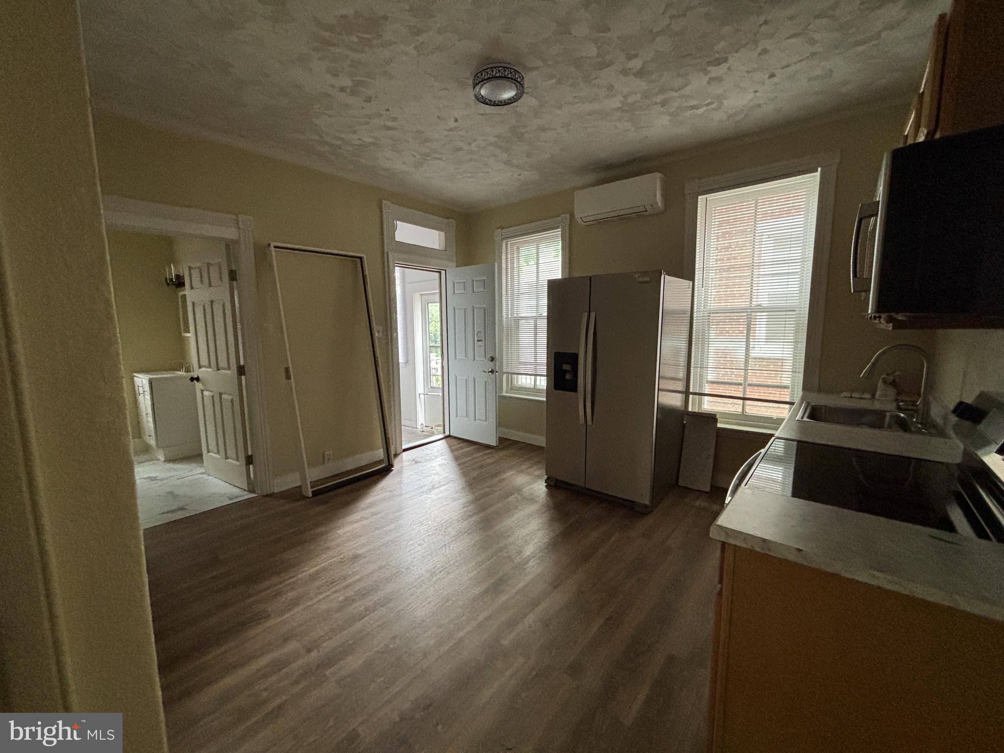 130 East 4th Street, Unit 1 Pottstown, PA 19464 - Photo 5 of 12 a view of a refrigerator in kitchen and an empty room with wooden floor windows