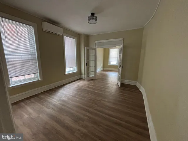 a view of an empty room with wooden floor and a window