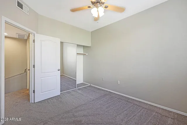an empty room with closet and a chandelier fan