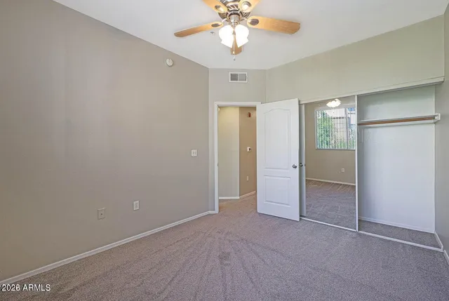 an empty room with closet and a chandelier fan