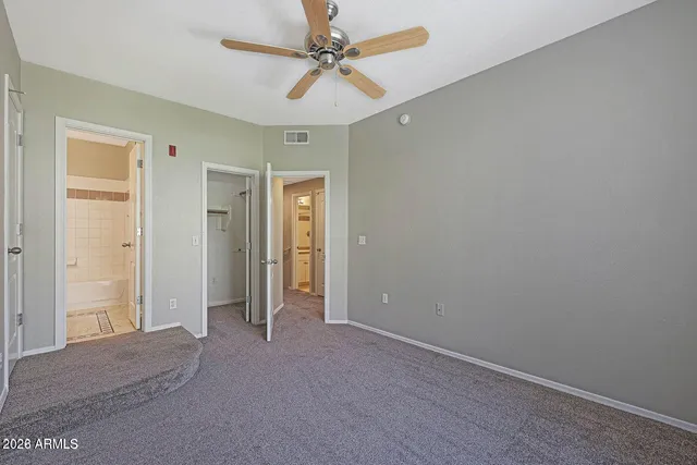 an empty room with closet and a ceiling fan