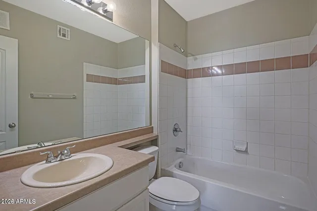 a bathroom with a granite countertop sink toilet a mirror and shower