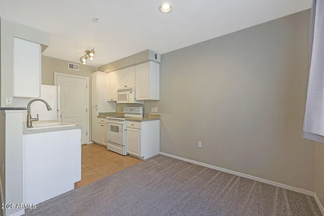 a kitchen with granite countertop white cabinets and white appliances