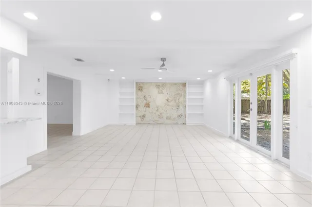 a view of an empty room with wooden floor and a kitchen