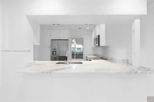 a large white kitchen with a sink and cabinets
