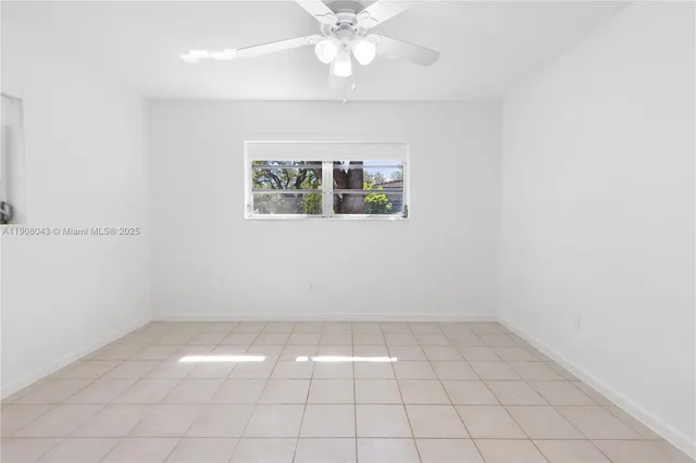an empty room with a ceiling fan and window
