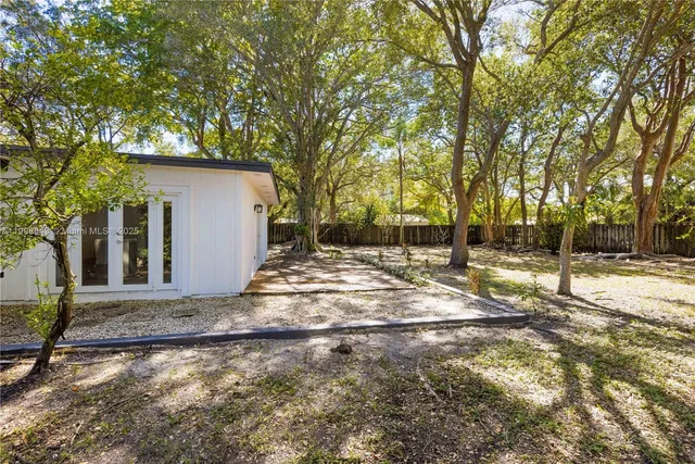 a backyard of a house with large trees and outdoor seating