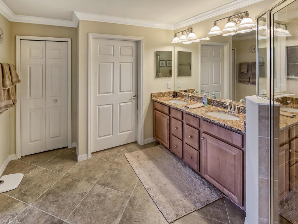 9114 Prima Way, Unit 102 Naples, FL 34113 - Photo 12 of 33 a spacious bathroom with a double vanity sink a mirror and a shower