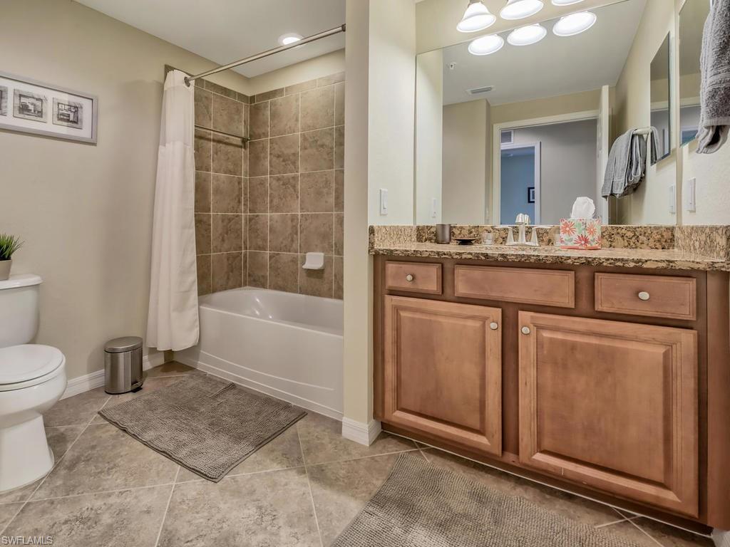 9114 Prima Way, Unit 102 Naples, FL 34113 - Photo 14 of 33 a bathroom with a granite countertop sink a toilet and a mirror