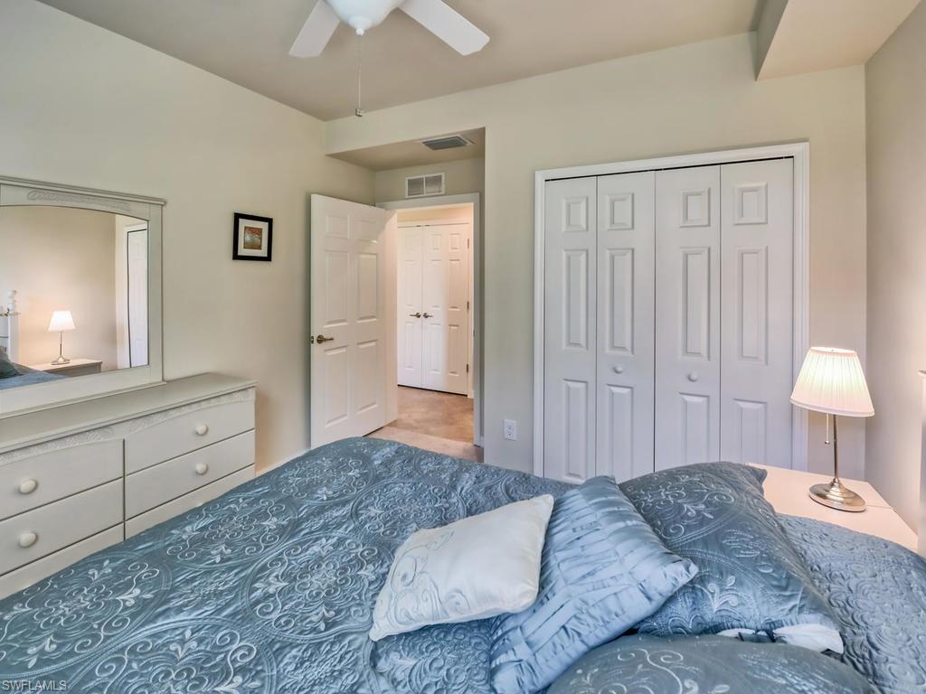 9114 Prima Way, Unit 102 Naples, FL 34113 - Photo 16 of 33 a bedroom with a bed and a lamp on dresser