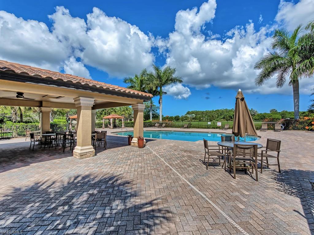 9114 Prima Way, Unit 102 Naples, FL 34113 - Photo 23 of 33 a view of a patio with a table and chairs under an umbrella with wooden floor