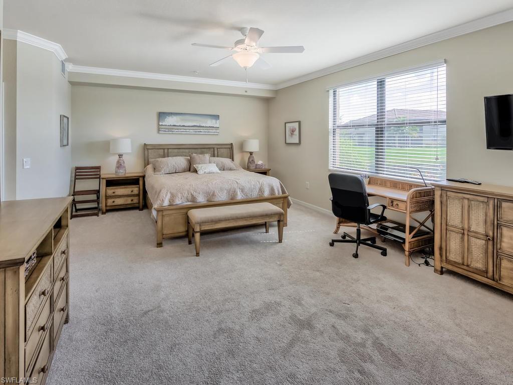 9114 Prima Way, Unit 102 Naples, FL 34113 - Photo 9 of 33 a bedroom with furniture and a flat screen tv