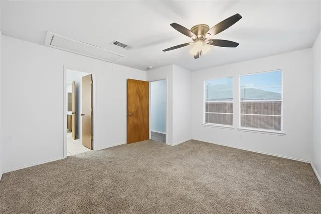 a view of an empty room with chandelier fan and windows