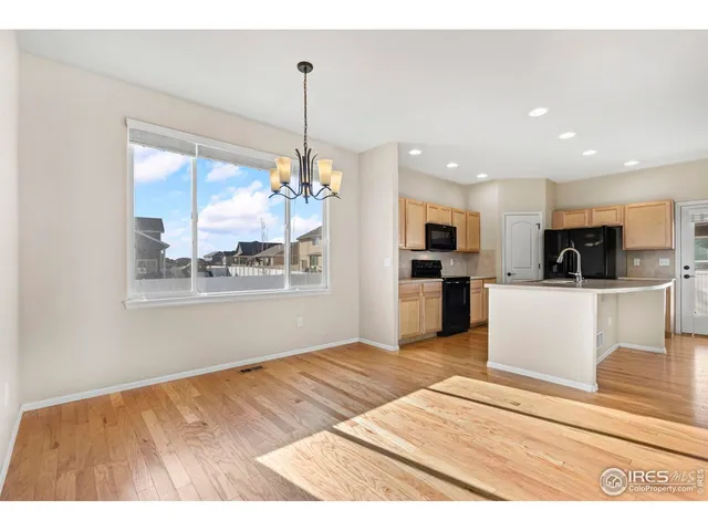 a view of a kitchen with kitchen island a sink wooden floor and a refrigerator