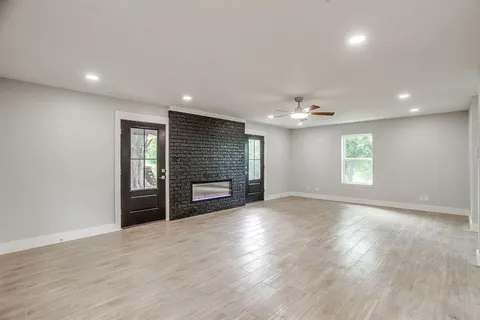 an empty room with wooden floor fireplace and windows