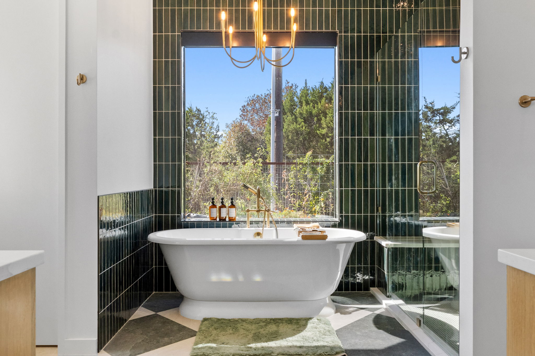 503 Happy Trail Dripping Springs, TX 78620 - Photo 15 of 38 Freestanding soaking tub with brass fixtures, set against a dark green vertical tile accent wall