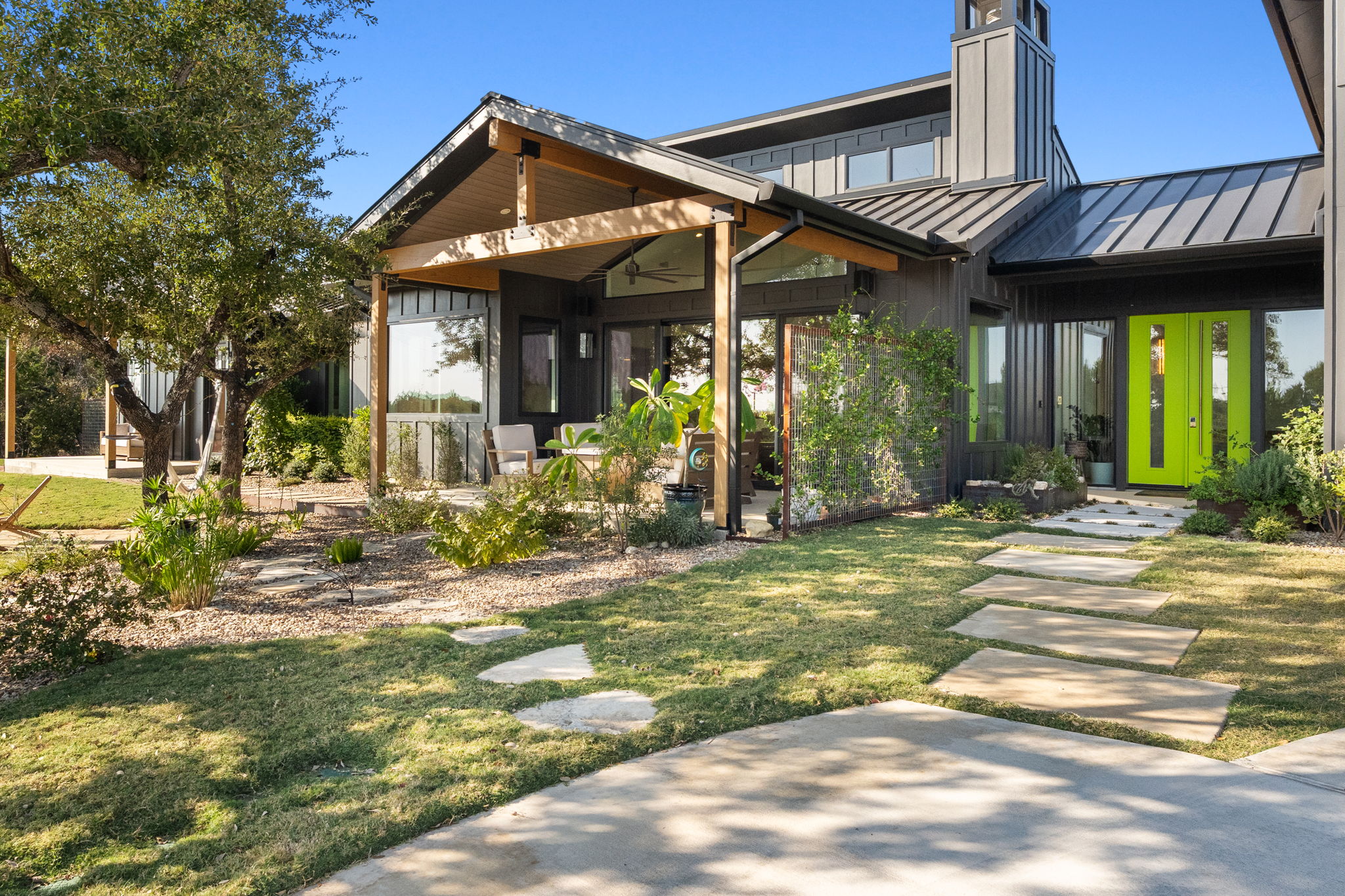 503 Happy Trail Dripping Springs, TX 78620 - Photo 2 of 38 Modern architectural design featuring a prominent green entry door, dark vertical siding, and a metal roof