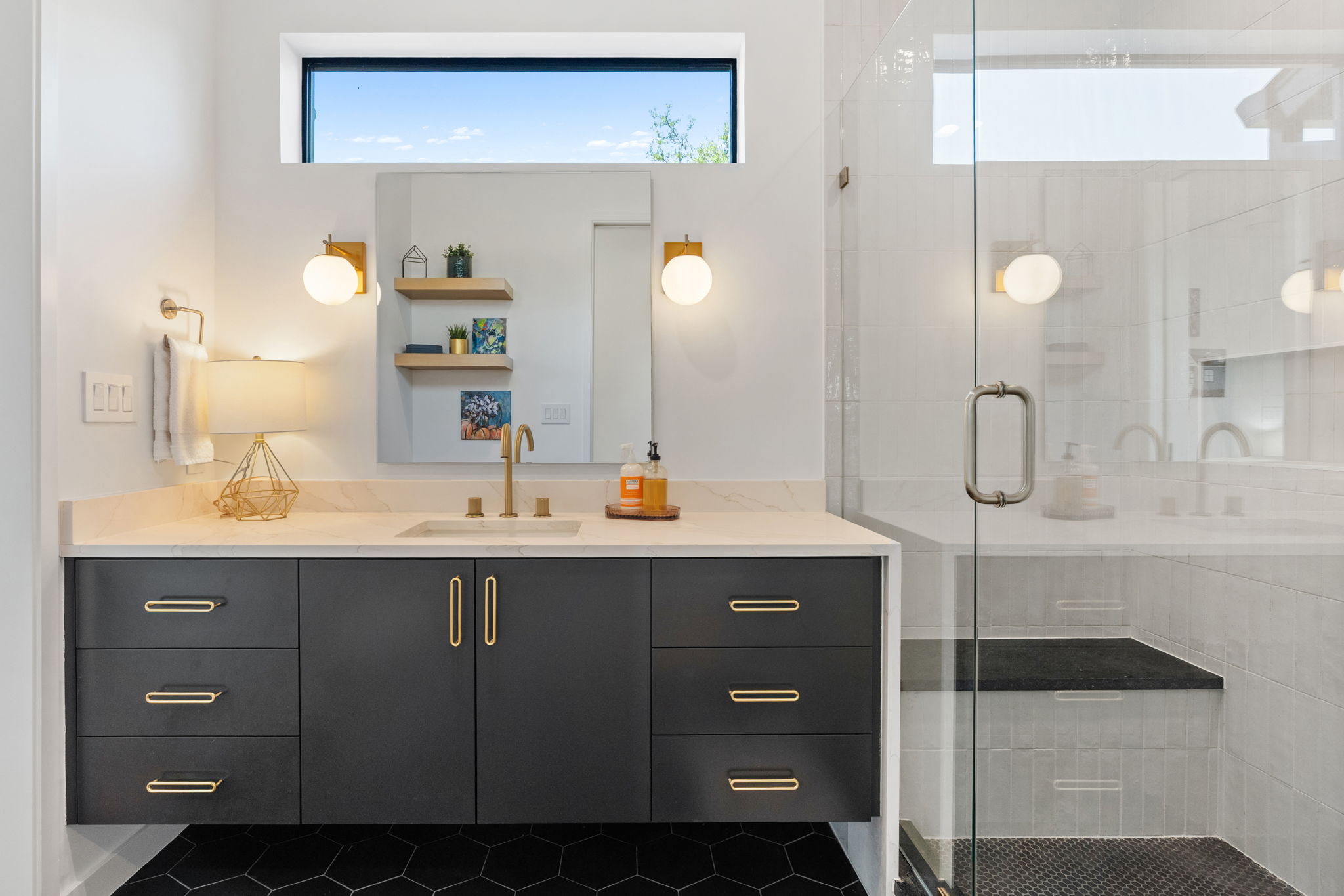 503 Happy Trail Dripping Springs, TX 78620 - Photo 22 of 38 Bathroom featuring a dark wood-finish floating vanity with a light-toned countertop, a glass-enclosed shower with a built-in bench, hexagonal black floor tiling, and a transom window