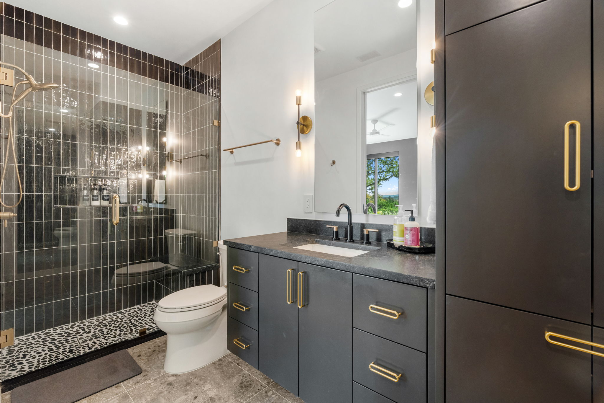 503 Happy Trail Dripping Springs, TX 78620 - Photo 24 of 38 Modern bathroom featuring a glass-enclosed shower with vertical dark tile and a pebbled floor