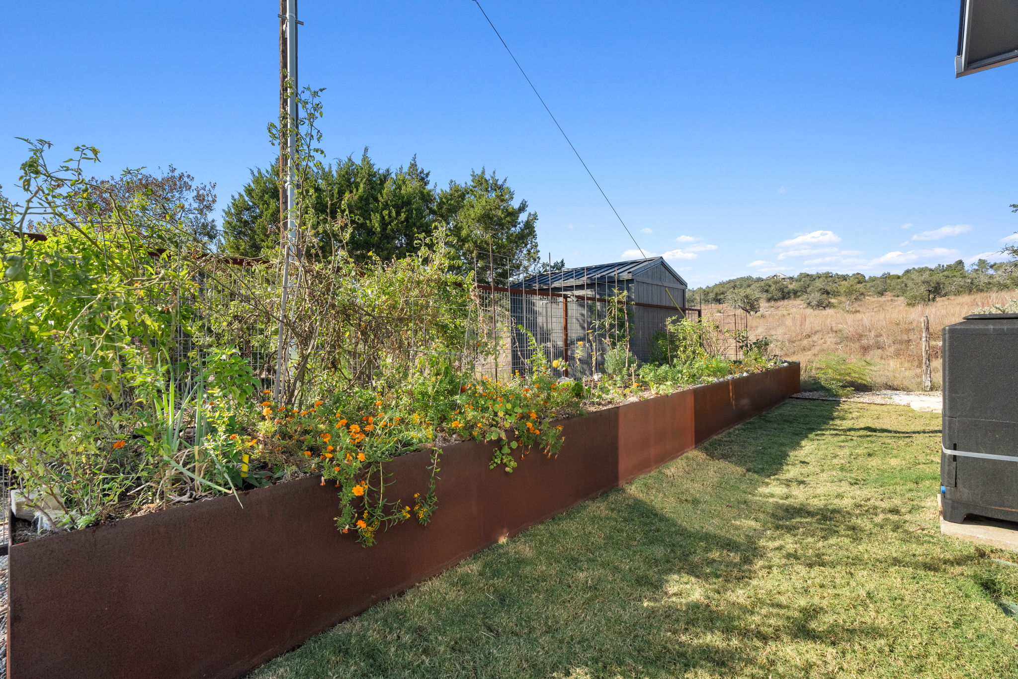 503 Happy Trail Dripping Springs, TX 78620 - Photo 35 of 38 Raised garden bed with established plantings, a detached storage shed, and a grassy lawn area