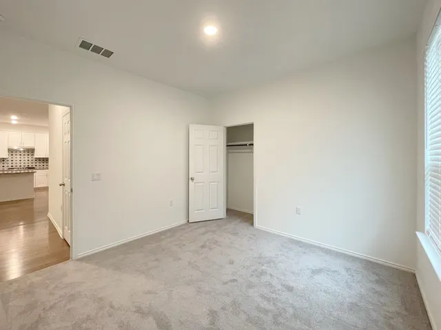 a view of an empty room and a kitchen