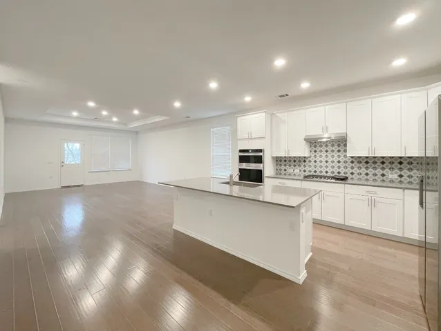a kitchen with stainless steel appliances a refrigerator sink and white cabinets