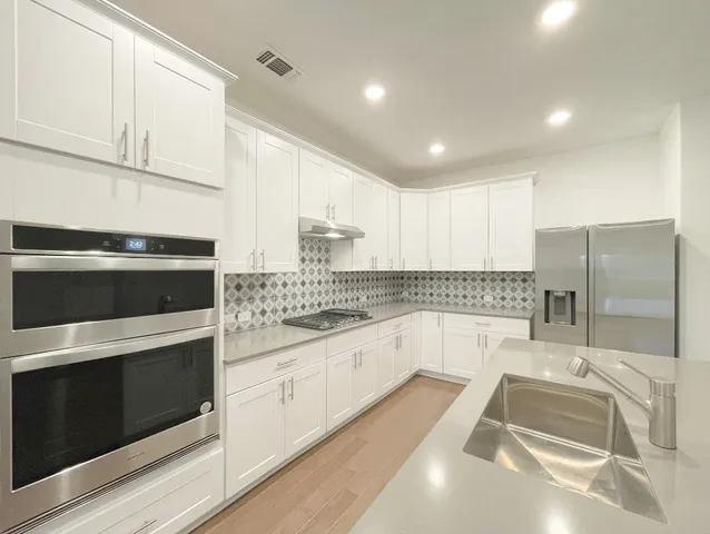 a kitchen with stainless steel appliances white cabinets a sink and a stove