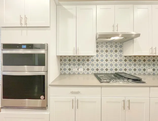a kitchen with a stove and white cabinets