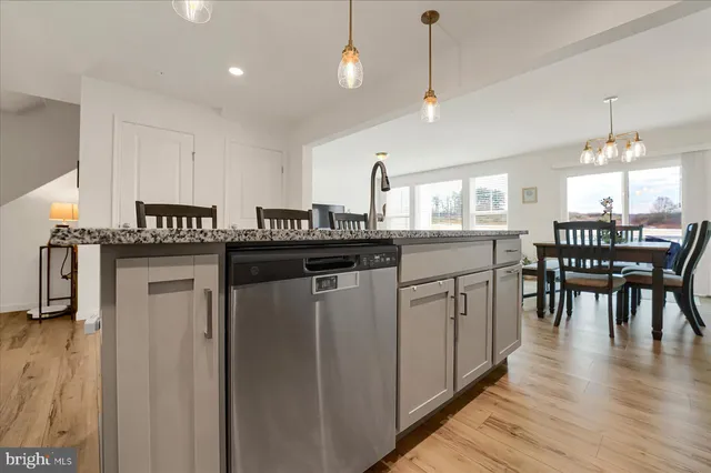 a kitchen with kitchen island granite countertop a sink cabinets and wooden floor