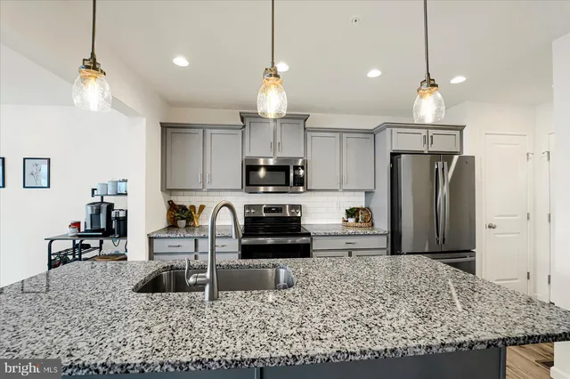 a kitchen with kitchen island granite countertop a refrigerator oven a stove a sink with a dining table and chairs