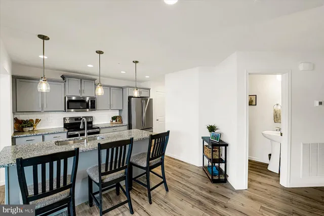 a kitchen with stainless steel appliances a dining table chairs stove refrigerator and cabinets