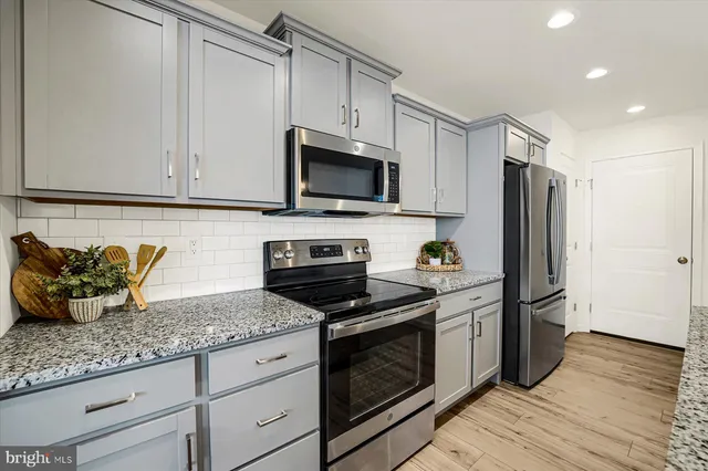 a kitchen with granite countertop a refrigerator stove and microwave