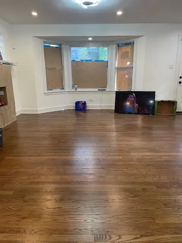a view of kitchen and empty room with wooden floor