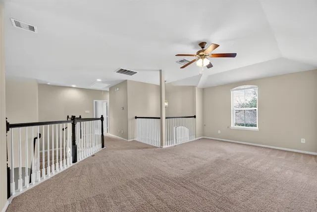 a view of an empty room and chandelier fan