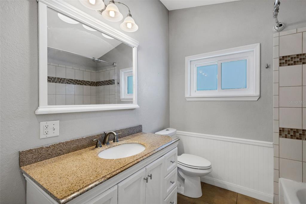 11436 Ridgewood Circle Seminole, FL 33772 - Photo 23 of 38 a bathroom with a granite countertop sink a toilet and a mirror