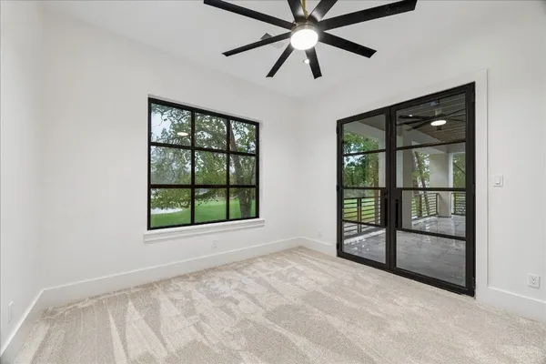 an empty room with chandelier fan and windows