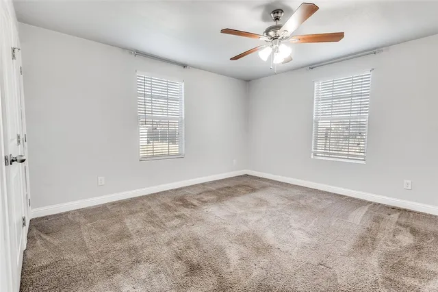 a view of an empty room with windows and chandelier fan