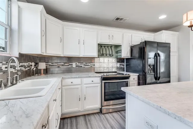 a kitchen with stainless steel appliances granite countertop a sink window and cabinets