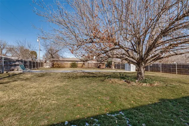 a backyard of a house with large trees and outdoor seating
