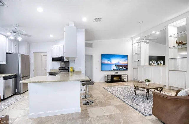 a living room with stainless steel appliances kitchen island furniture and a flat screen tv