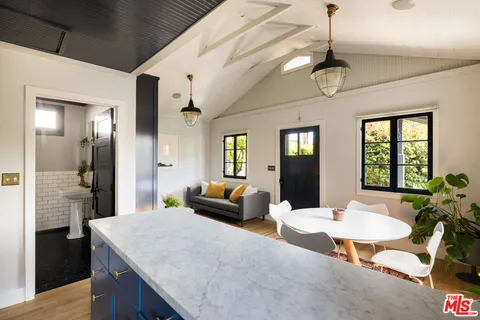a living room with stainless steel appliances kitchen island granite countertop furniture a rug and white walls