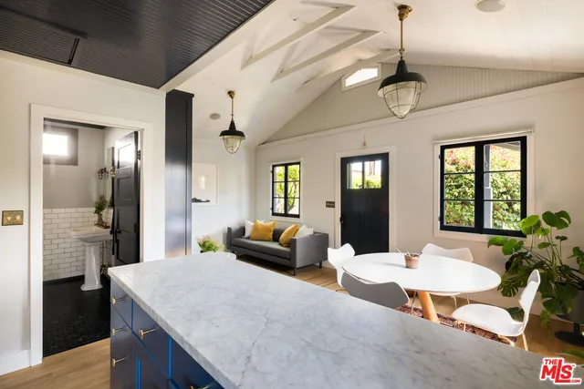 a living room with stainless steel appliances kitchen island granite countertop furniture a rug and white walls
