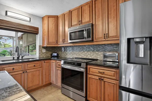 a kitchen with granite countertop cabinets stainless steel appliances and a window