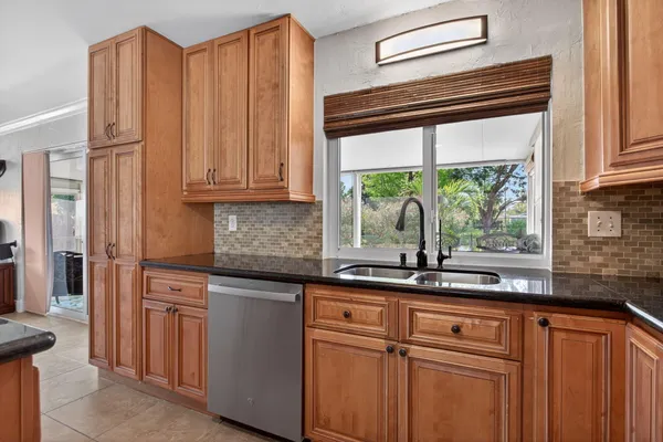 a kitchen with stainless steel appliances granite countertop white cabinets and a window