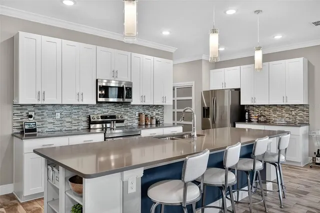 a kitchen with stainless steel appliances granite countertop a stove top oven a sink dishwasher a dining table and chairs with wooden floor