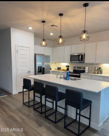 a kitchen with stainless steel appliances kitchen island granite countertop a table chairs and a refrigerator